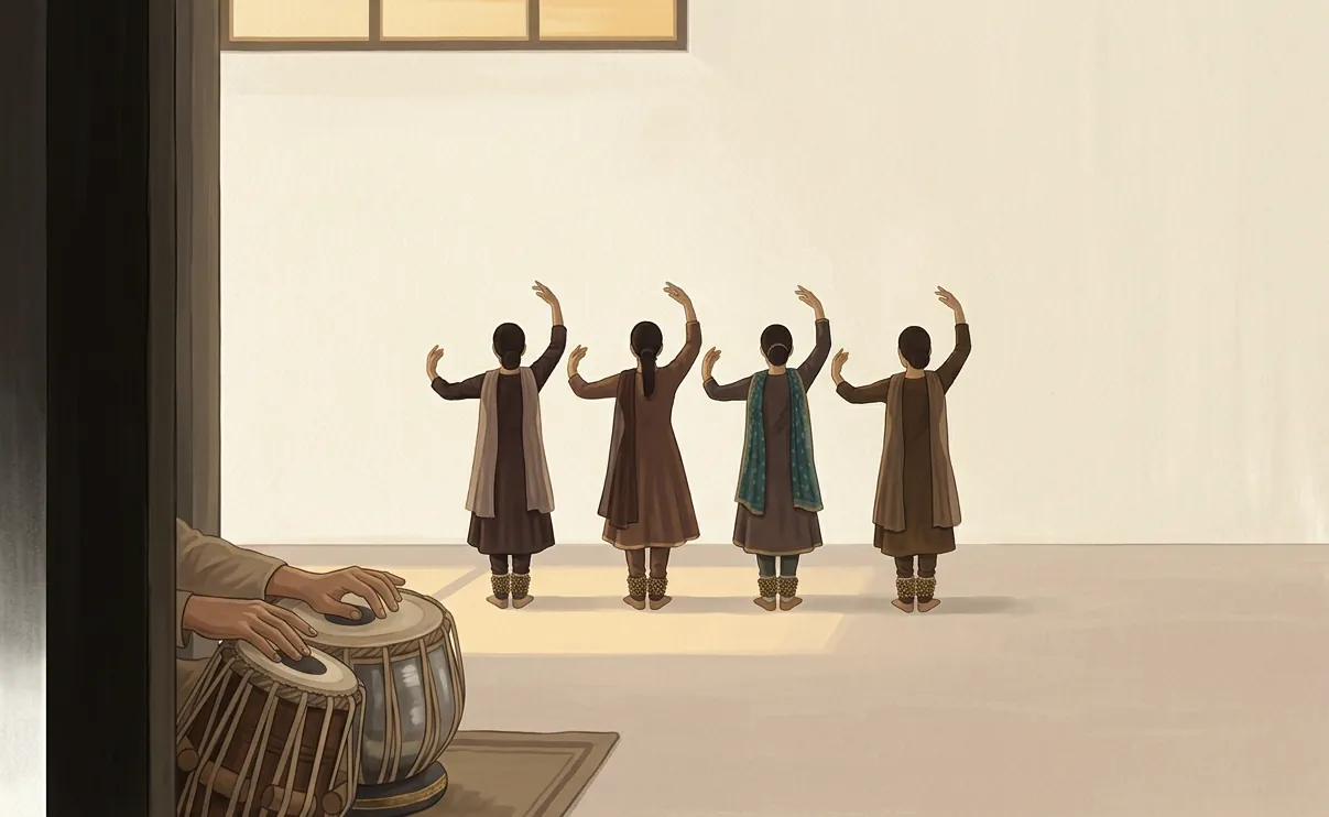 A Kathak class glimpsed from the doorway: the guru's hands on the tabla in the foreground, four students standing in a row beyond, seen from behind.